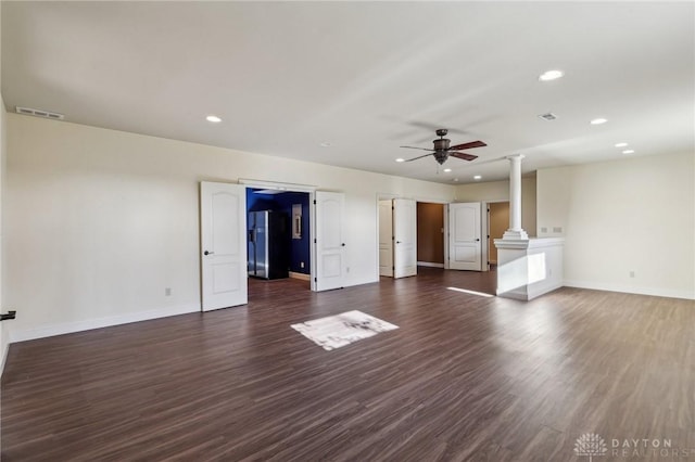 unfurnished living room featuring ornate columns, ceiling fan, and dark wood-type flooring