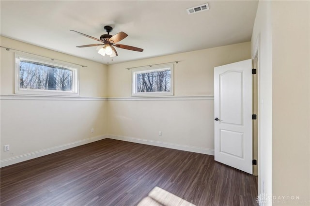 spare room featuring dark hardwood / wood-style flooring, a wealth of natural light, and ceiling fan