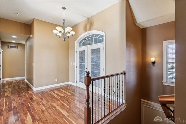 foyer featuring french doors, wood-type flooring, and an inviting chandelier