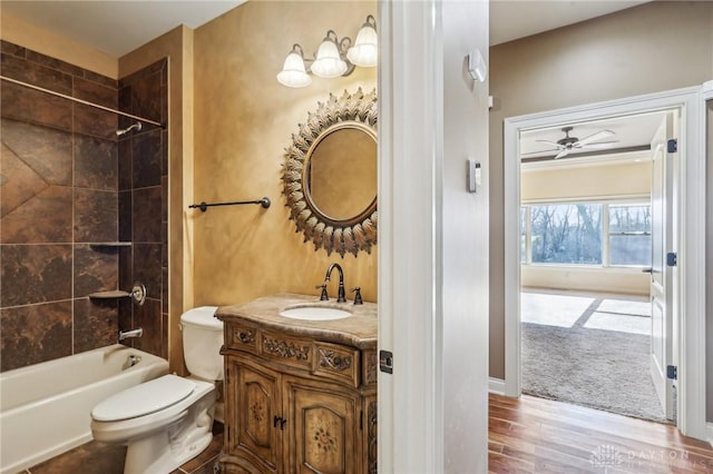 full bathroom with ceiling fan, wood-type flooring, toilet, vanity, and tiled shower / bath