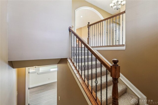 stairway with wood-type flooring and a notable chandelier