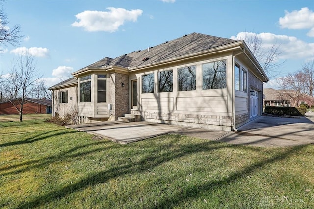 rear view of property featuring a patio, a garage, and a lawn