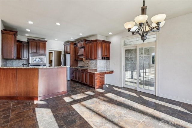 kitchen featuring decorative backsplash, light stone counters, appliances with stainless steel finishes, and a chandelier