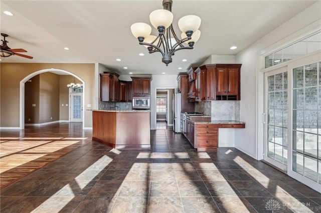 kitchen featuring decorative backsplash, a wealth of natural light, light stone countertops, and stainless steel microwave