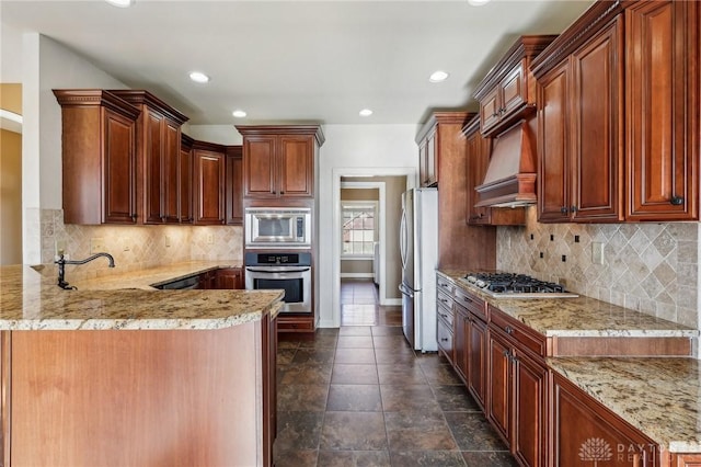 kitchen with light stone counters, premium range hood, kitchen peninsula, backsplash, and appliances with stainless steel finishes