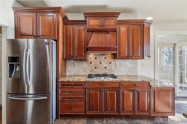 kitchen featuring custom range hood, backsplash, stainless steel appliances, and light stone counters