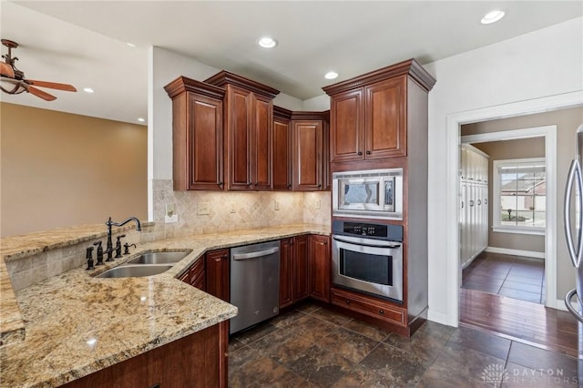 kitchen with sink, decorative backsplash, light stone countertops, appliances with stainless steel finishes, and kitchen peninsula