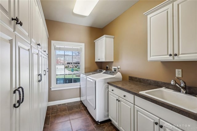 clothes washing area featuring cabinets, washing machine and clothes dryer, and sink