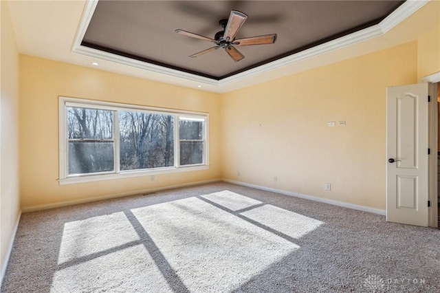 carpeted spare room featuring a tray ceiling, ceiling fan, and crown molding