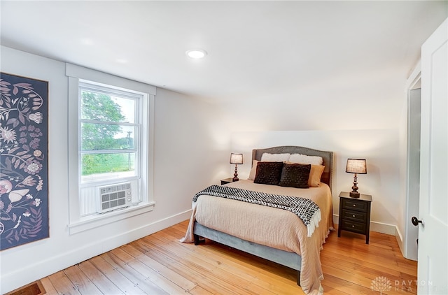 bedroom with cooling unit and light hardwood / wood-style flooring