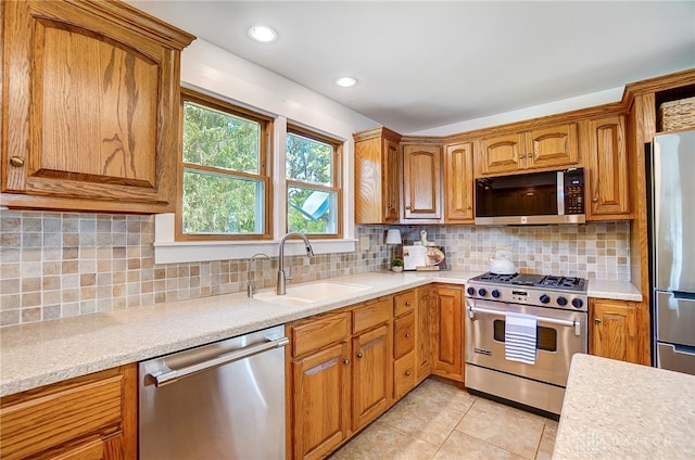 kitchen featuring sink, light tile patterned floors, appliances with stainless steel finishes, and decorative backsplash