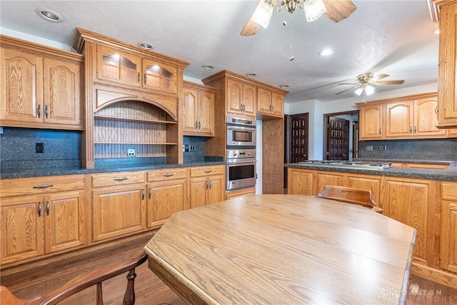 kitchen with ceiling fan, dark hardwood / wood-style flooring, appliances with stainless steel finishes, and tasteful backsplash