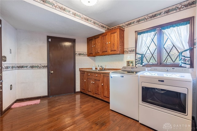 clothes washing area featuring hardwood / wood-style floors, washer and dryer, cabinets, and sink