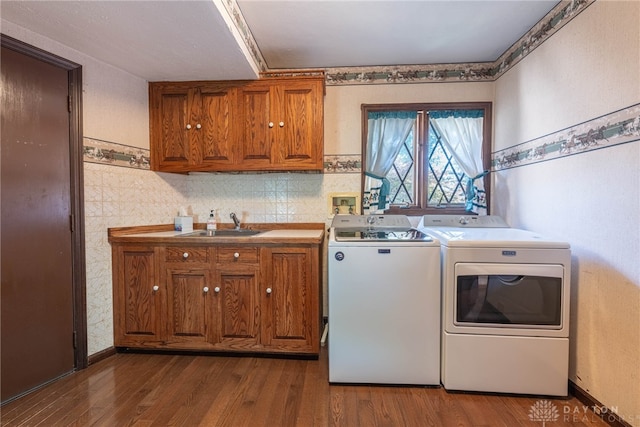 laundry room with cabinets, dark hardwood / wood-style flooring, sink, and washing machine and clothes dryer