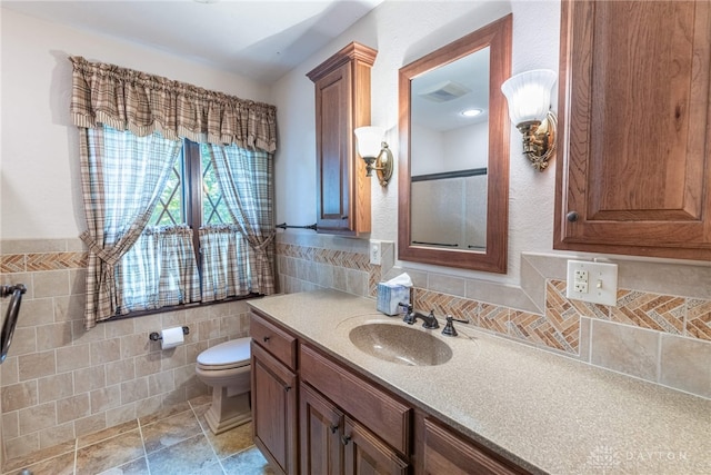 bathroom with vanity, tile walls, and toilet