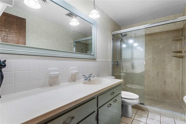 bathroom featuring toilet, tile patterned flooring, vanity, decorative backsplash, and tile walls