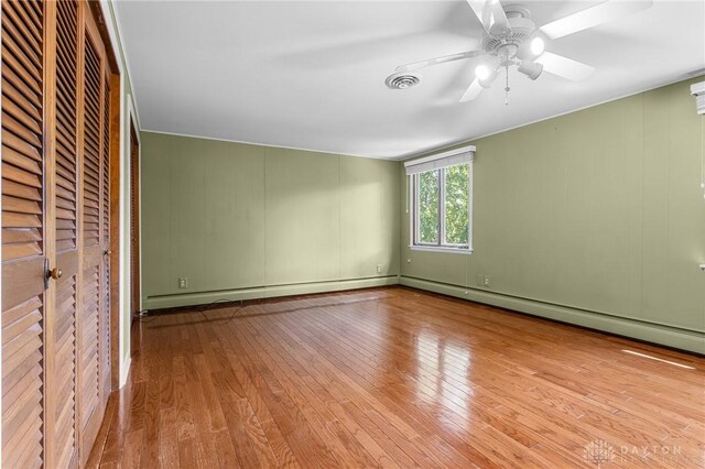 unfurnished bedroom featuring a baseboard heating unit, light hardwood / wood-style flooring, and ceiling fan