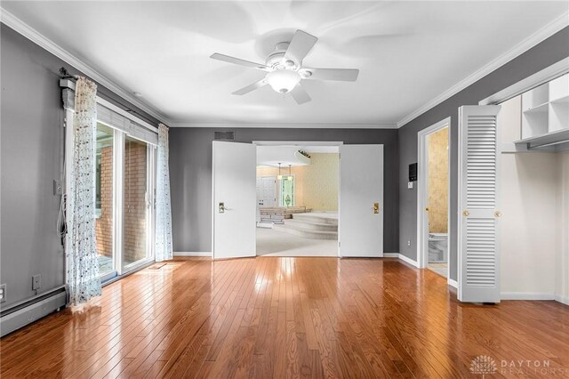 unfurnished bedroom featuring ensuite bath, multiple windows, and hardwood / wood-style floors