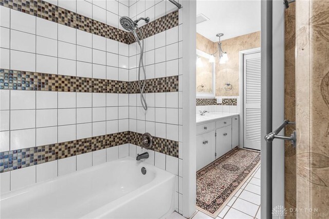 bathroom with tile patterned flooring, vanity, and tiled shower / bath