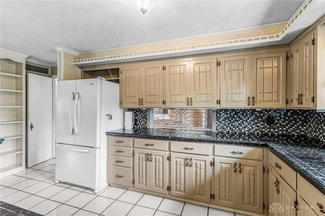 kitchen with a textured ceiling, light tile patterned floors, tasteful backsplash, ornamental molding, and white refrigerator