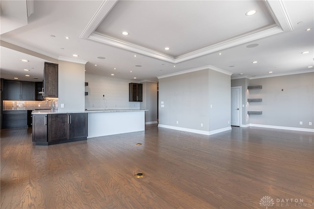 unfurnished living room featuring a tray ceiling, dark wood finished floors, and baseboards