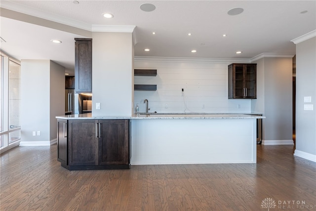 kitchen featuring glass insert cabinets, dark wood-style flooring, ornamental molding, and light stone countertops