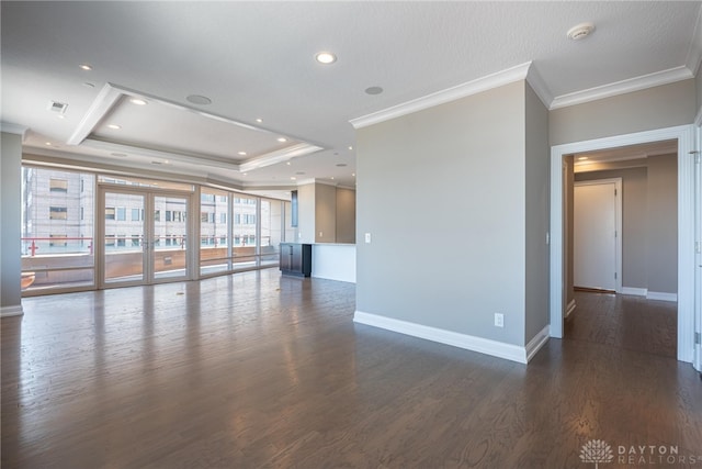 spare room featuring dark wood finished floors, recessed lighting, a raised ceiling, ornamental molding, and baseboards