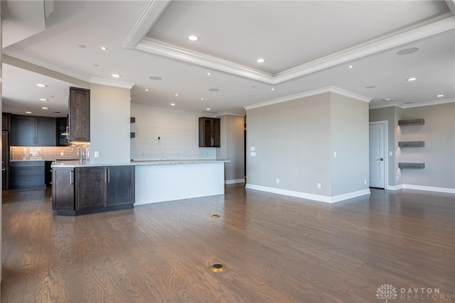 unfurnished living room featuring a tray ceiling, crown molding, recessed lighting, dark wood-type flooring, and baseboards