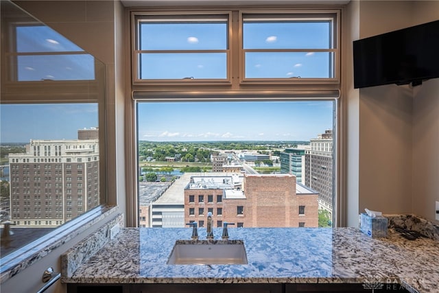 interior space featuring a view of city, light stone counters, and a sink