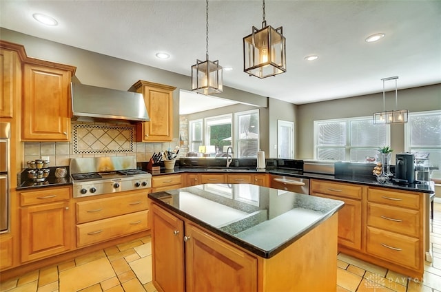 kitchen featuring decorative light fixtures, appliances with stainless steel finishes, sink, wall chimney exhaust hood, and a kitchen island