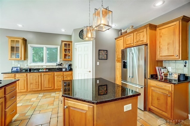 kitchen featuring backsplash, a center island, pendant lighting, and stainless steel refrigerator with ice dispenser