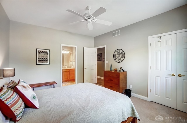 carpeted bedroom featuring ceiling fan, a closet, and ensuite bath