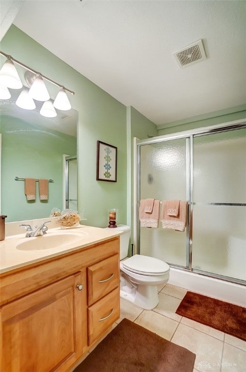 bathroom with tile patterned flooring, walk in shower, toilet, and vanity