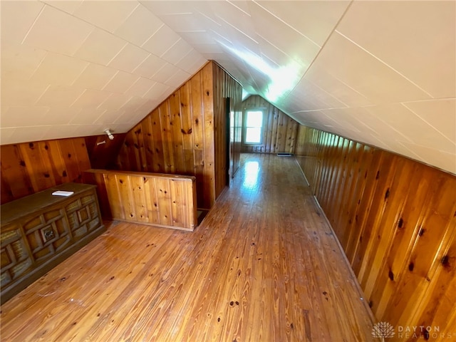 additional living space featuring vaulted ceiling, hardwood / wood-style floors, and wooden walls