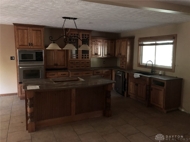 kitchen featuring sink, light tile patterned floors, built in microwave, decorative light fixtures, and stainless steel oven