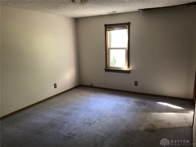 carpeted empty room featuring a textured ceiling