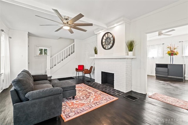 living room featuring ceiling fan, dark hardwood / wood-style flooring, and a brick fireplace