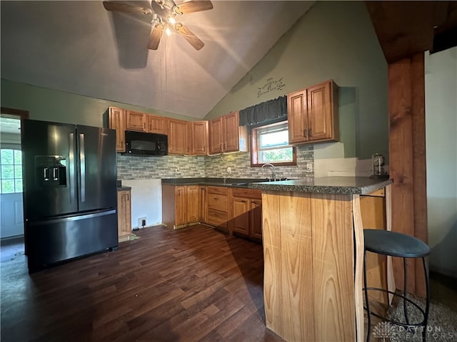 kitchen featuring refrigerator with ice dispenser, plenty of natural light, dark hardwood / wood-style floors, and kitchen peninsula