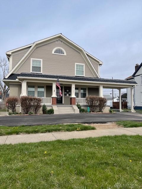 view of front of home with a front lawn, a porch, and a carport