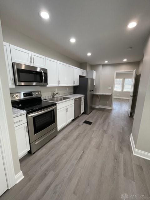 kitchen featuring white cabinets, appliances with stainless steel finishes, sink, and light hardwood / wood-style floors