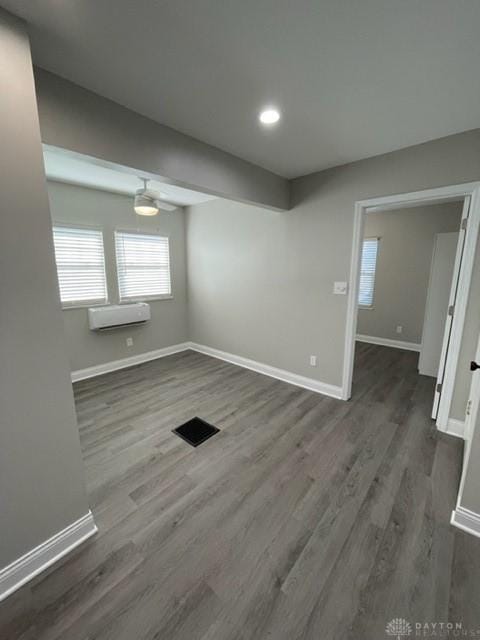 empty room with dark wood-type flooring and an AC wall unit