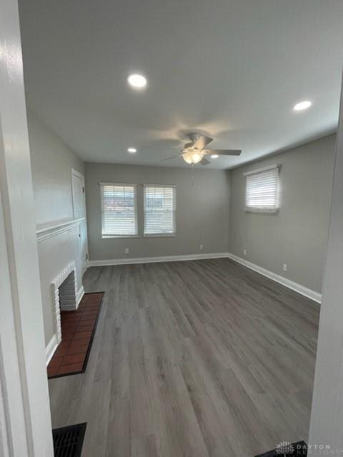 unfurnished living room with a brick fireplace, hardwood / wood-style flooring, and ceiling fan