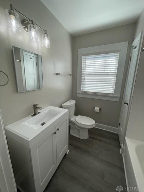 bathroom featuring wood-type flooring, toilet, vanity, and a bathing tub