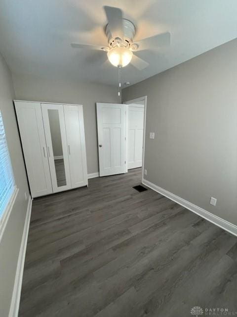 unfurnished bedroom featuring ceiling fan, dark hardwood / wood-style flooring, and a closet