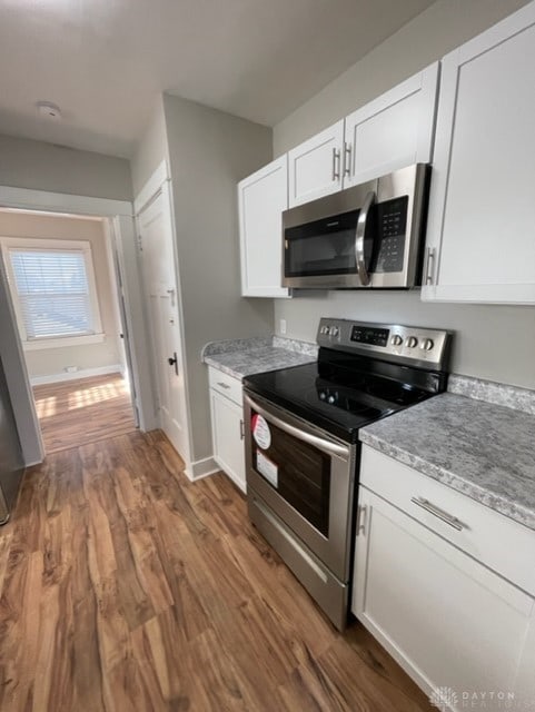 kitchen with white cabinets, appliances with stainless steel finishes, and dark hardwood / wood-style flooring