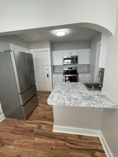 kitchen featuring sink, kitchen peninsula, white cabinets, and stainless steel appliances