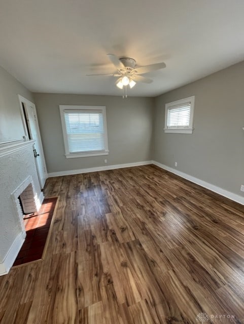 interior space featuring ceiling fan, wood-type flooring, and a brick fireplace