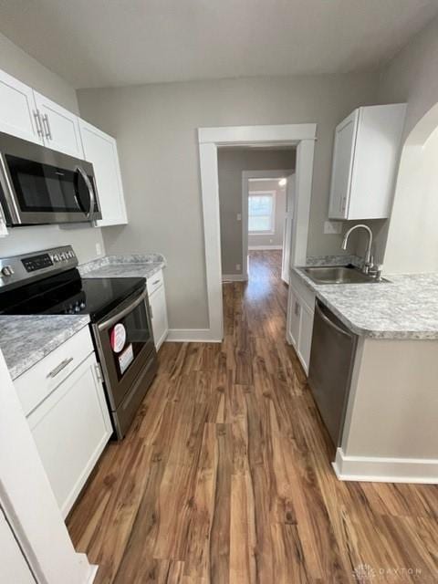 kitchen featuring appliances with stainless steel finishes, dark hardwood / wood-style flooring, white cabinetry, and sink