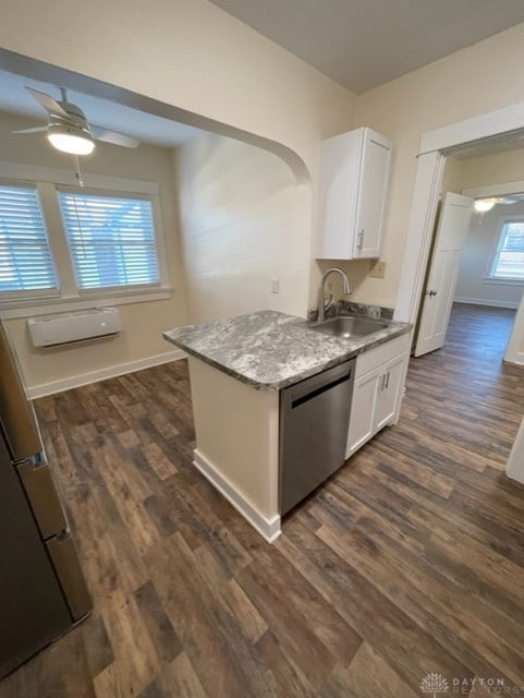 kitchen with stainless steel dishwasher, sink, a wall mounted air conditioner, dark wood-type flooring, and white cabinets