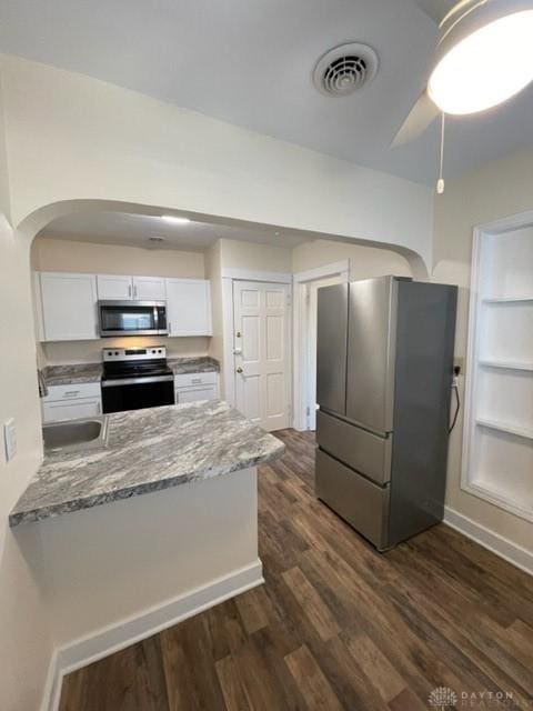 kitchen featuring kitchen peninsula, stainless steel appliances, dark wood-type flooring, light stone countertops, and white cabinets